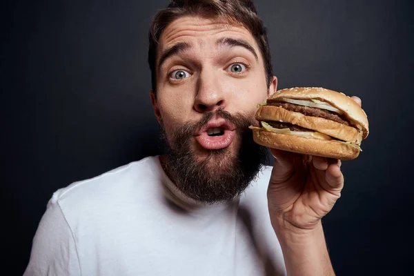 Hombre comiendo hamburguesa comida rápida restaurante Gourmet comer fondo oscuro — Foto de Stock