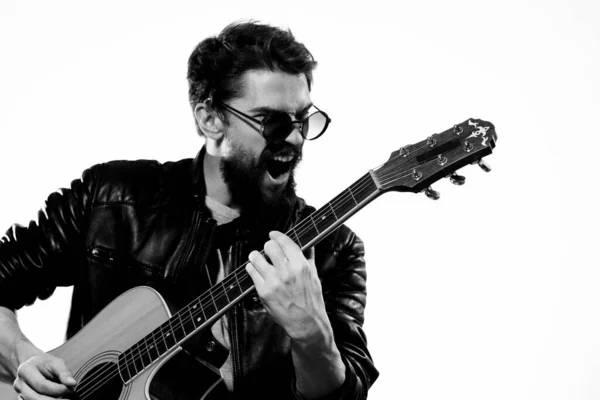 Um homem segura uma guitarra em suas mãos emoções musicais jaqueta de couro preto óculos escuros estúdio luz fundo — Fotografia de Stock