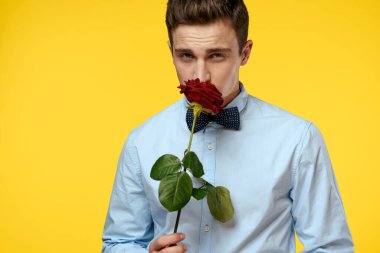 Sarı arka planda kırmızı gül ve açık gömlek papyonlu bir beyefendinin portresi.