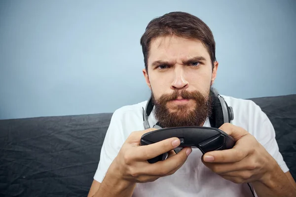 A man sits on a sofa with a gamepad in his hand. Leisure lifestyle game console — Stock Photo, Image