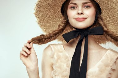 Siyah kurdeleli, saman şapkalı ve açık renk arka planda giyinmiş güzel bir kız.