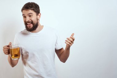 Elinde bir kupa bira ve beyaz tişörtlü açık renk bıyıklı sakallı bir adam.