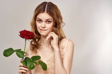 Elinde gül olan kızıl saçlı bir kadın açık arkaplanda duygu modeli portresi.