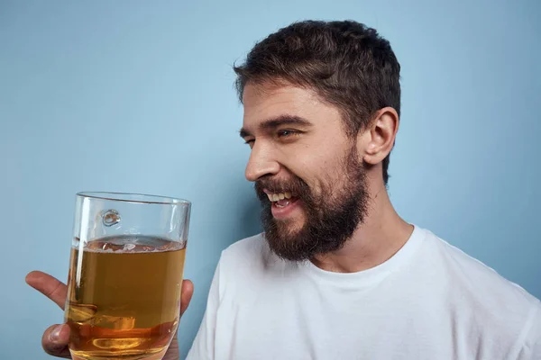 Homme joyeux dans un T-shirt blanc avec une tasse de bière fond bleu ivre — Photo