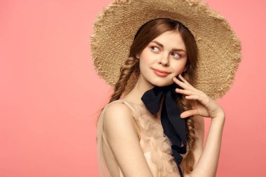 Hasır şapkalı bir kızın portresi pembe arka plan duyguları yakın plan güzel yüz modeli örgüler.