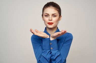 Açık arkaplanda kırmızı dudaklı ve mavi gömlekli güzel bir kadının portresi.