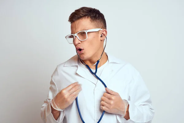 Médecin dans une robe médicale avec un stéthoscope et des lunettes sur un fond clair portrait de vue recadrée — Photo