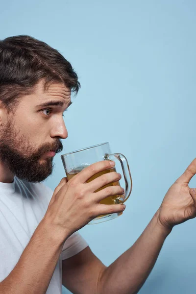 Bearded man öl mugg alkohol vit t-shirt sida visa blå bakgrund — Stockfoto