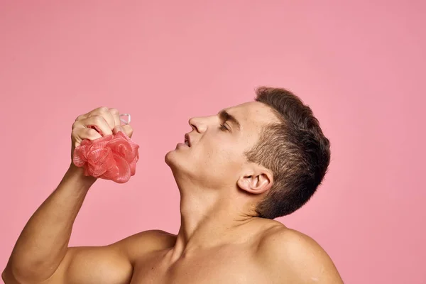 Uomo nudo con un panno in mano su uno sfondo rosa vista ritagliata — Foto Stock