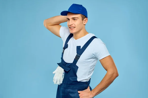 Working man in uniform of gloves loader rendering service blue background — Stock Photo, Image