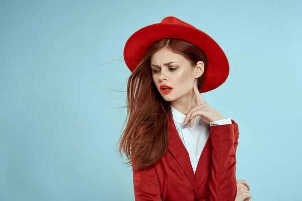 Mooie vrouw in rode hoed jas rode lippen lang haar charme blauwe achtergrond — Stockfoto