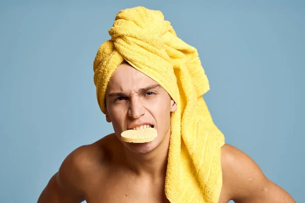 Een man met een gele handdoek op zijn hoofd en een zachte spons voor het reinigen van de huid cosmetologie model — Stockfoto