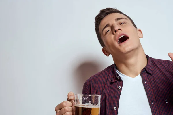 Fylld man med en mugg öl semester alkohol livsstil i en röd skjorta känslor ljus bakgrund — Stockfoto