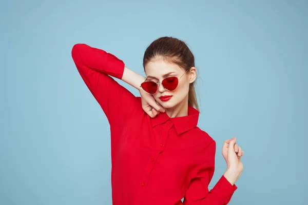 Kobieta z ciemnymi okularami czerwony usta urok koszula studio niebieski tło — Zdjęcie stockowe