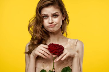 Sarı arka planda kırmızı gülü olan hoş bir kız duygu modelini kırpmış.