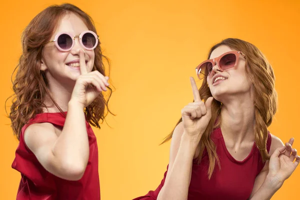 Gelukkige zussen in rode jurken op een gele achtergrond hebben plezier en gesticulating Copy Space — Stockfoto