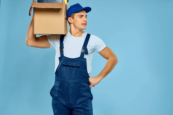 Trabalhador homem em caixa uniforme com ferramentas carregador entrega azul fundo — Fotografia de Stock