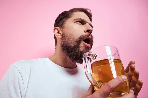 Homme ivre avec une grande tasse de bière Sur un fond rose et un T-shirt blanc vue détendue d'une barbe épaisse — Photo