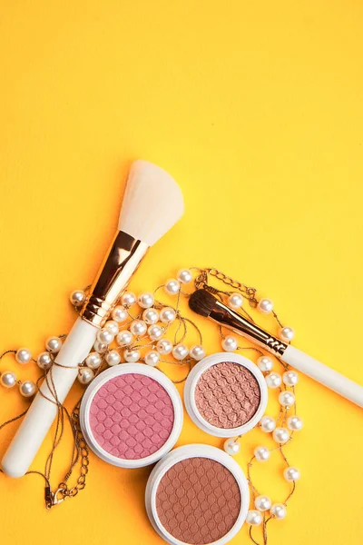 Eyeshadows dan kuas makeup pada latar belakang kuning top view kosmetik profesional — Stok Foto
