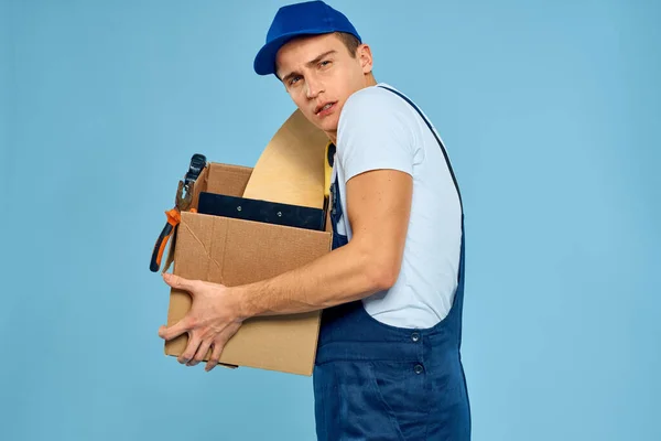 Trabalhador homem em caixa uniforme com ferramentas carregador entrega azul fundo — Fotografia de Stock