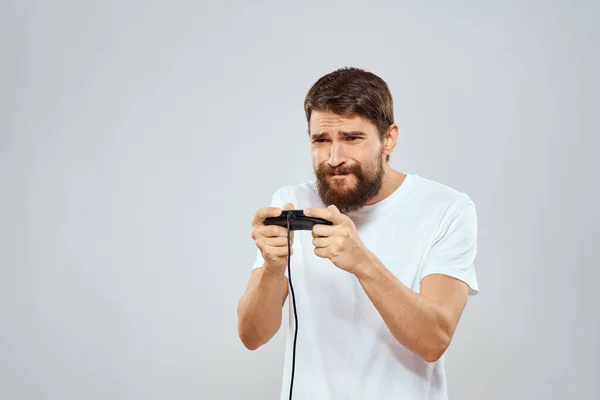 Un hombre con un mando en sus manos jugando juegos ocio estilo de vida tecnología blanco camiseta fondo claro —  Fotos de Stock