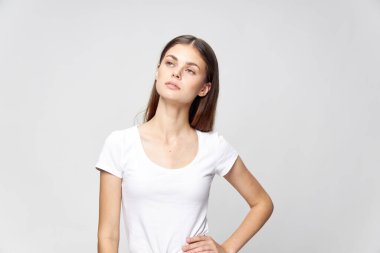 Tişörtlü bir kadın elini kemerde tutuyor.