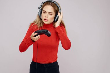 Kulaklıklı bir kadın elinde Joystick ile oyun oynuyor eğlence amaçlı eğlence amaçlı yaşam tarzı kırmızı gömlek gri arka plan