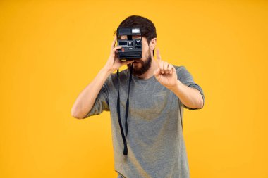 Profesyonel fotoğraf makinesi olan bir erkek fotoğrafçı. Profesyonel Yaratıcı yaklaşım stüdyo sarı arka plan