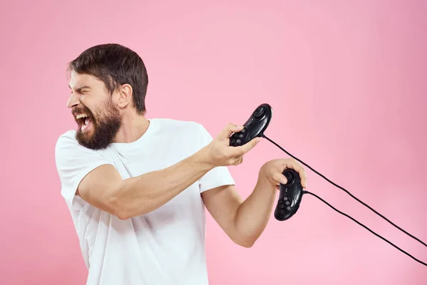 Hombre con dos joysticks en manos divertido juego tecnología estilo de vida rosa fondo —  Fotos de Stock