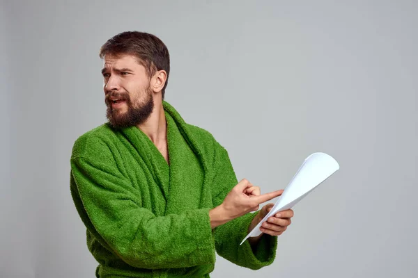 Эмоциональный мужчина в зеленом платье с свернутым листом бумаги на светлом фоне обрезанный вид — стоковое фото