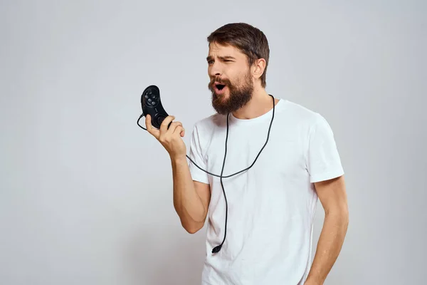 Un hombre con un mando en sus manos jugando juegos ocio estilo de vida tecnología blanco camiseta fondo claro — Foto de Stock