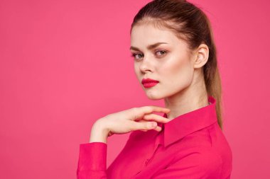 Pembe tişörtlü çekici bir kız parlak makyajlı kırmızı dudaklar ellerle işaret ediyor Boşluğu kopyala
