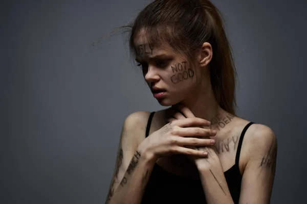 Aufgebrachte Frau mit beleidigendem Schriftzug auf ihrem Körper auf grauem Hintergrund, die sich mit abgeschnittenen Händen berührt — Stockfoto