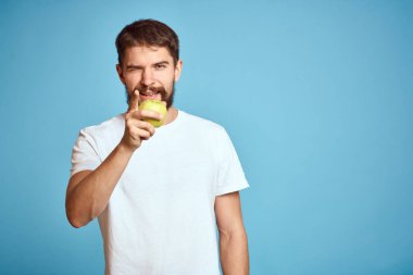 Mavi arka planda yeşil elmalı enerjik bir adam elleriyle uzay duygularını taklit eder.