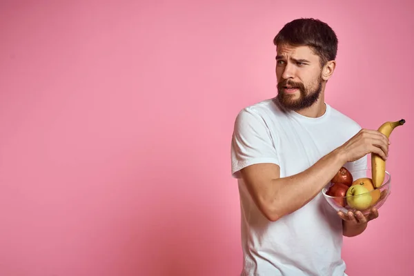 Hombre enérgico con fruta fresca en una taza sobre un espacio de copia de fondo rosa — Foto de Stock