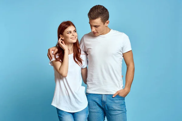 Homem e mulher apaixonados em jeans e uma camiseta em um fundo azul abraçar uns aos outros e se divertir — Fotografia de Stock