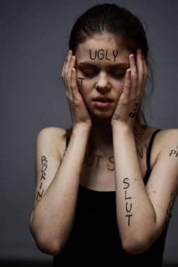 Vücut hüsranı üzerine yazıları olan bir kadın duygularını vurgulayarak yaşam tarzını gri arka planda tutuyor.