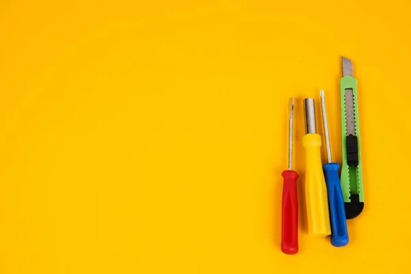 Chaves de fenda de faca de papelaria e ferramentas de construção em equipamentos de fundo amarelo para a indústria de reparação — Fotografia de Stock