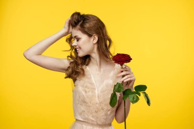 Sarı arka planda kırmızı gül ve gece elbisesi içinde romantik bir kadın.