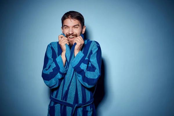 Un hombre con una túnica azul sobre un fondo claro gestos con sus manos modelo de ropa de casa —  Fotos de Stock