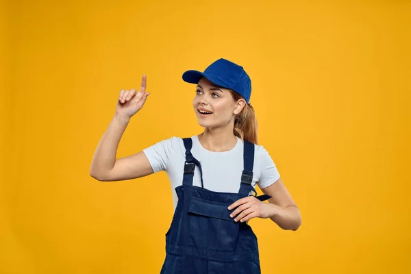 Женщина в рабочей форме голубая кепка доставки курьерской службы желтый фон — стоковое фото