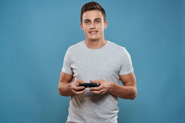 Un hombre con un joystick en sus manos entretenimiento tecnología de ocio videojuegos fondo azul camiseta blanca —  Fotos de Stock
