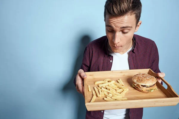 Mann mit Holzpalette Fast Food Pommes Frites Hamburger Hunger Diät Essen blauer Hintergrund — Stockfoto