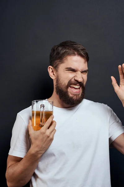 Homme avec une tasse de bière dans un t-shirt blanc émotions style de vie ivre sur un fond sombre isolé — Photo