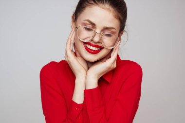 Kırmızı gömlekli şık bir kadın açık arkaplanda eğlenceli duygular parlak makyaj gözlükleri çekici bir görünüş. 