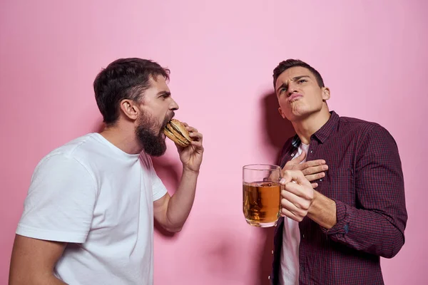Dwóch mężczyzn pije piwo przyjaźń pijany alkohol styl życia różowy tło — Zdjęcie stockowe