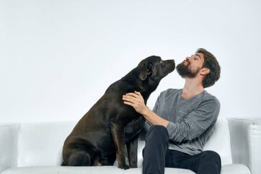 Kanepede evcil köpeği olan bir adam. Arkadaşlarıyla eğleniyor.