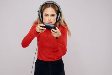 Kulaklıklı bir kadın elinde Joystick ile oyun oynuyor eğlence amaçlı eğlence amaçlı yaşam tarzı kırmızı gömlek gri arka plan