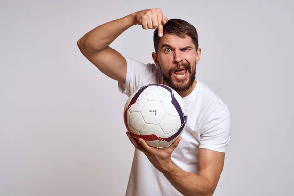 Allenatore maschile con un pallone da calcio in mano su uno sfondo leggero spiegazione energetica dei movimenti — Foto Stock