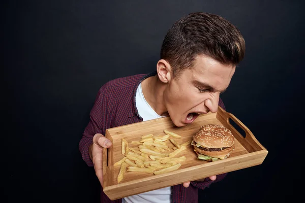 man holding wooden pallet with fast food in his hands diet food hunger lifestyle dark background